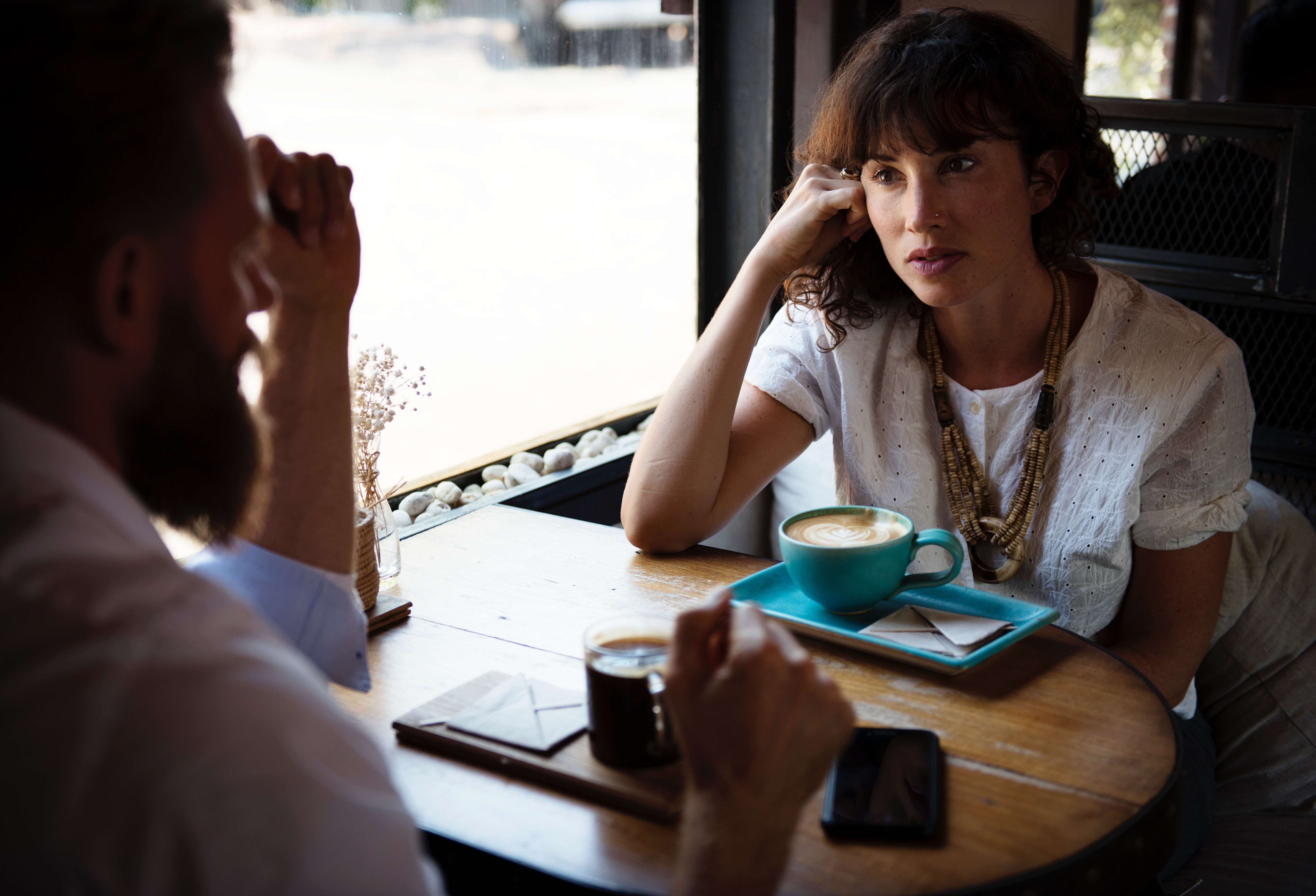 Two people talking in an uncomfortable conversation over coffee.