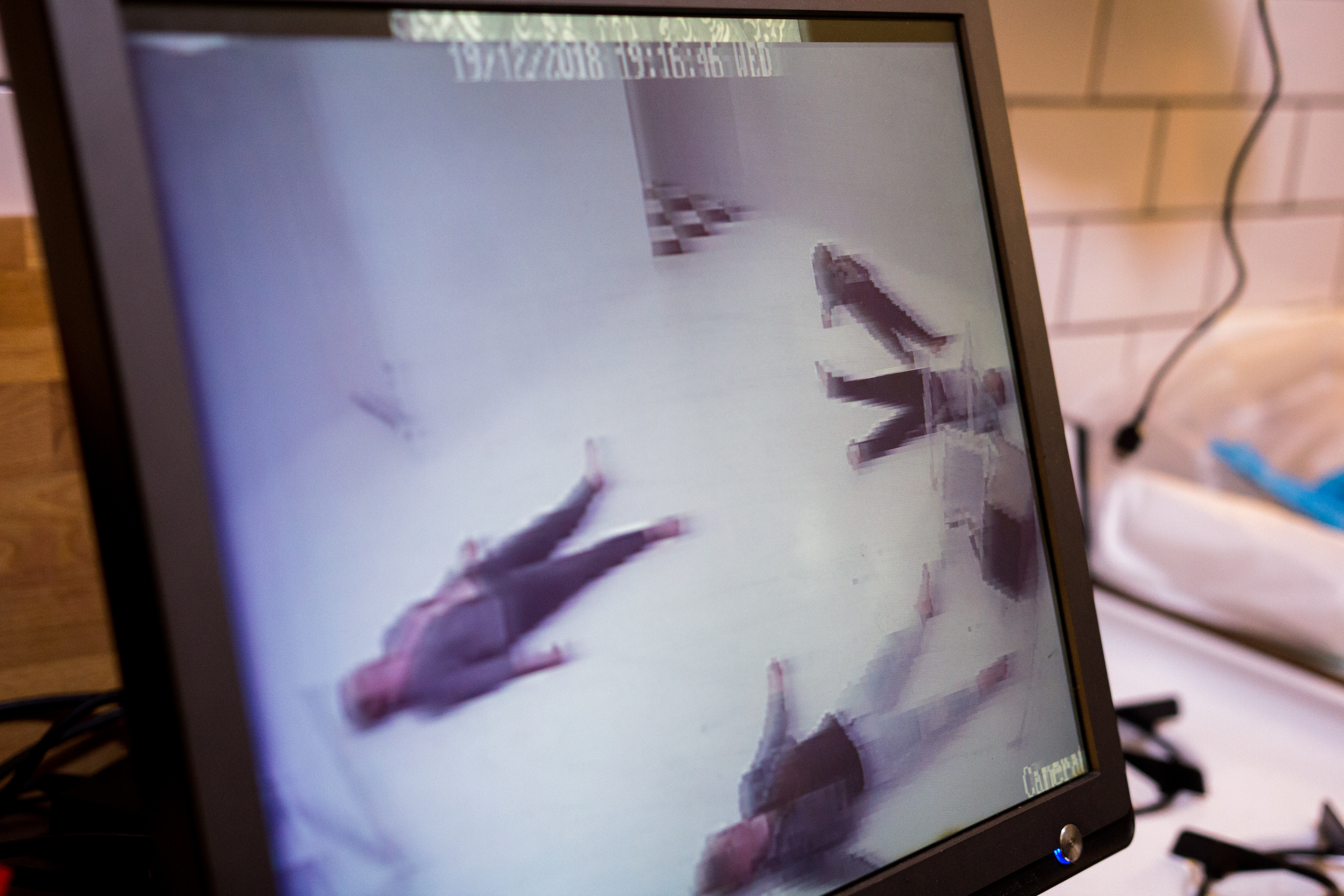 Dead bodies on a floor seen over a camera screen.